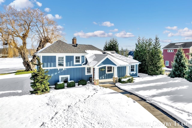 view of front of home featuring board and batten siding, a shingled roof, and a chimney