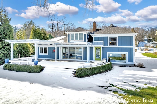 rear view of property featuring a chimney, roof with shingles, a pergola, board and batten siding, and a patio area