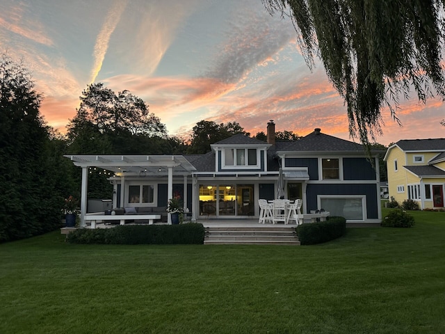 back of property featuring a chimney, an attached garage, a yard, a patio area, and a pergola