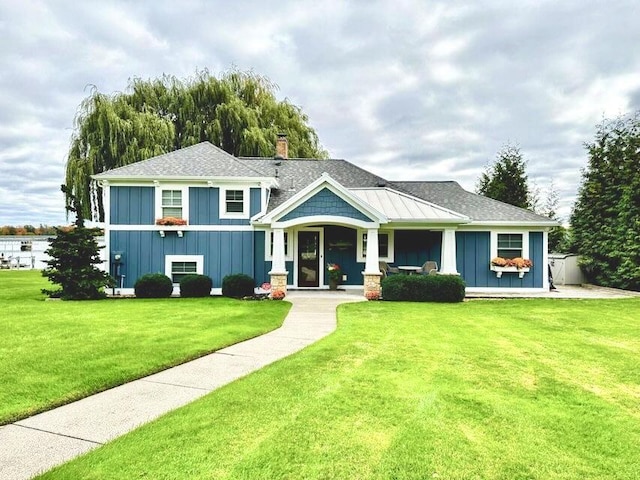 view of front of home featuring a front lawn, board and batten siding, a chimney, and a shingled roof