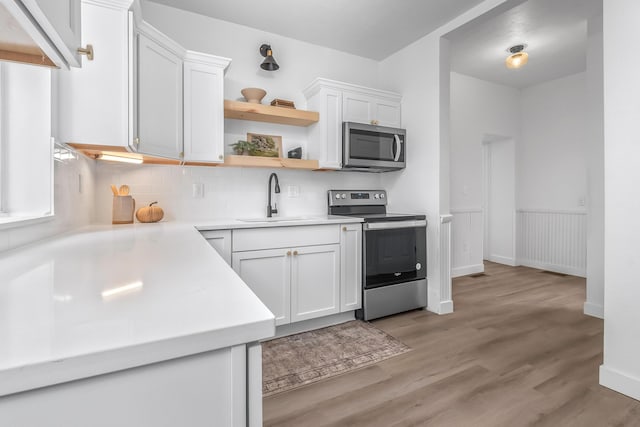 kitchen featuring stainless steel appliances, sink, white cabinets, and light hardwood / wood-style flooring