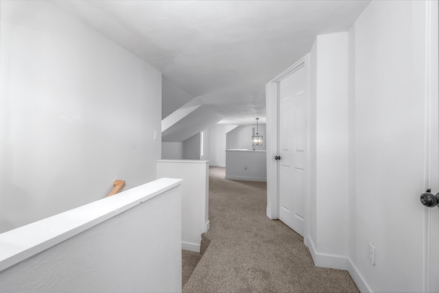 hallway with vaulted ceiling and light colored carpet