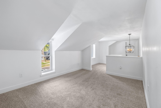 additional living space with vaulted ceiling, a healthy amount of sunlight, a chandelier, and carpet floors