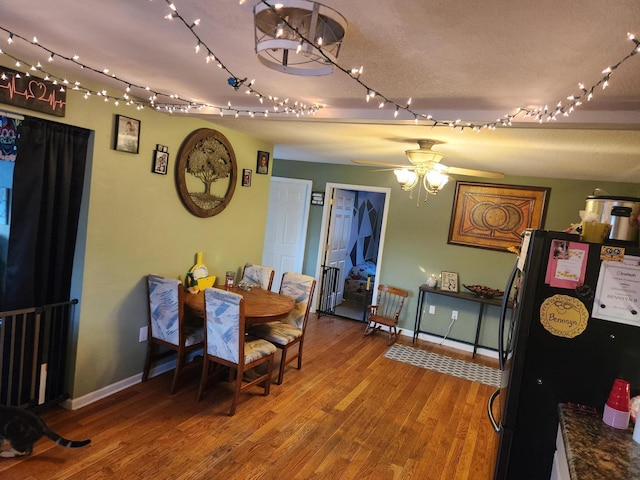 dining area with wood-type flooring and ceiling fan with notable chandelier