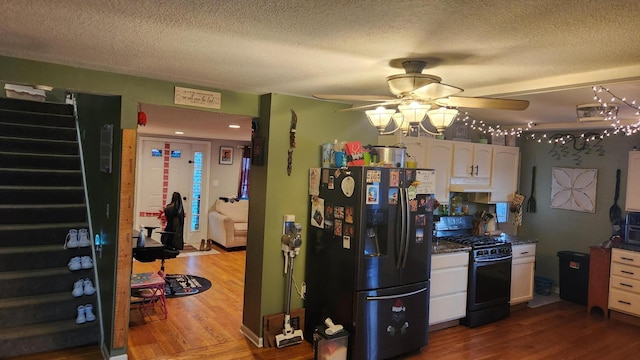 kitchen with hardwood / wood-style flooring, white cabinetry, black gas stove, and stainless steel fridge with ice dispenser