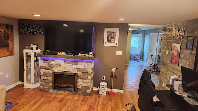 living room featuring hardwood / wood-style flooring and a stone fireplace