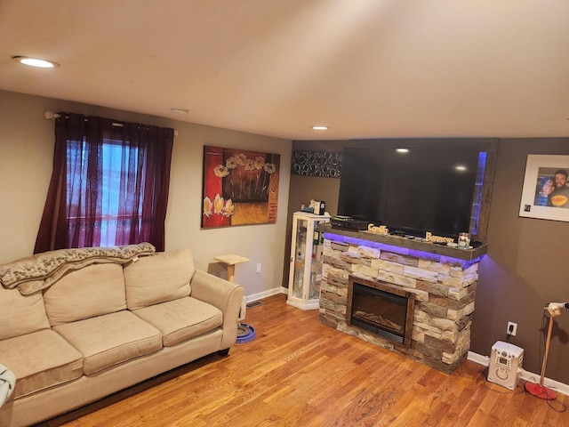 living room with a stone fireplace and hardwood / wood-style floors