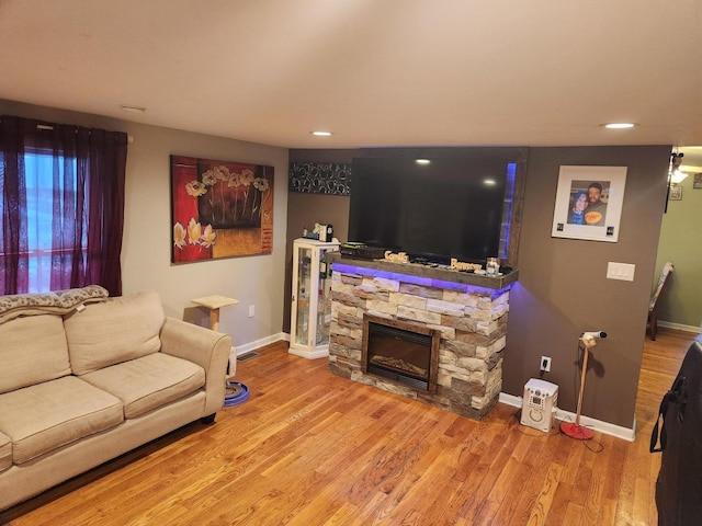 living room featuring a stone fireplace and hardwood / wood-style flooring