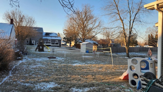 view of yard with a shed, an outdoor fire pit, a playground, and a trampoline