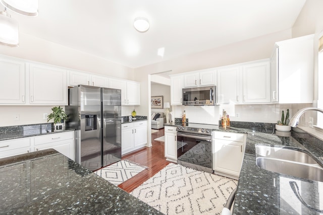 kitchen featuring stainless steel appliances, white cabinetry, sink, and dark stone countertops