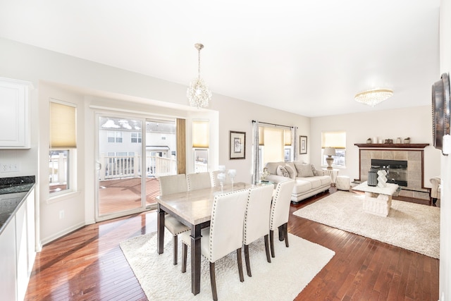 dining room featuring a tile fireplace, a barn door, hardwood / wood-style floors, and a chandelier