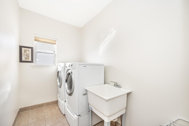 washroom with sink, light tile patterned floors, and washing machine and clothes dryer