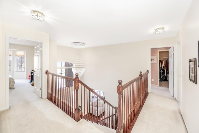 hall with light colored carpet and a chandelier