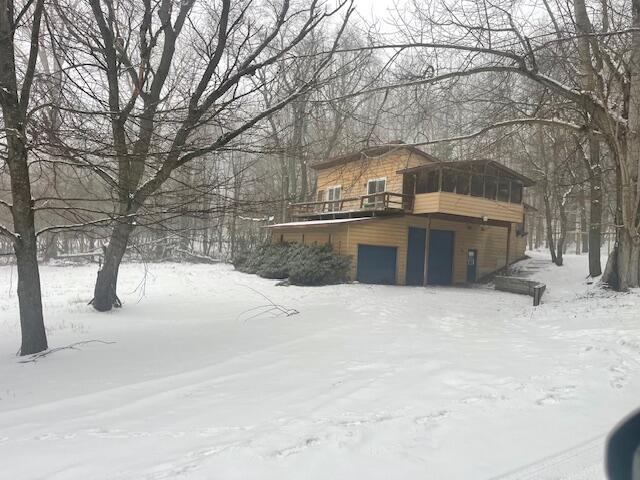 snow covered property featuring a wooden deck and a sunroom