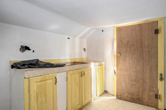 kitchen with light brown cabinetry and vaulted ceiling