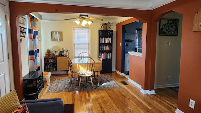 dining room with visible vents, light wood-style flooring, arched walkways, crown molding, and baseboards