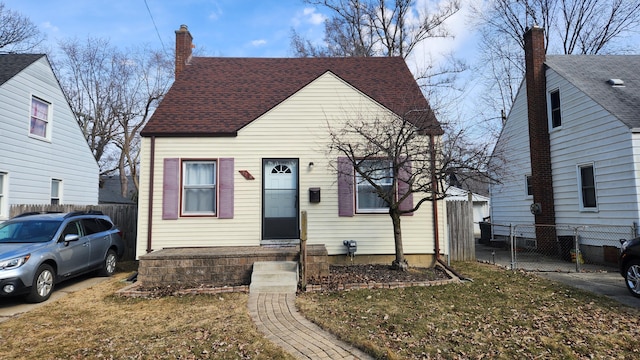 view of front of home with fence, a chimney, and a shingled roof