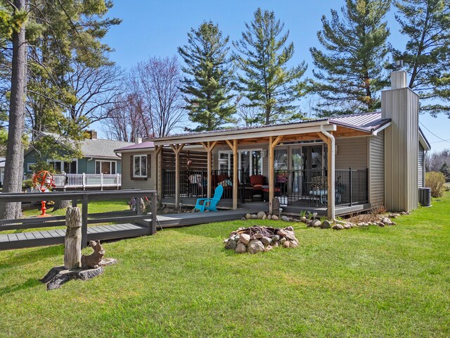 3509 N Shore Dr, Sears, MI 49679 - rear view of property with a chimney, metal roof, a deck, central AC, and a yard