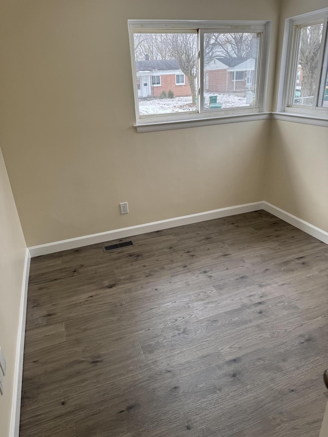 spare room with a healthy amount of sunlight and dark hardwood / wood-style flooring