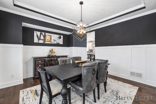 dining area featuring a raised ceiling, crown molding, dark hardwood / wood-style floors, and a notable chandelier