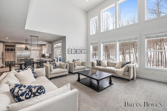 carpeted living room featuring an inviting chandelier and a towering ceiling