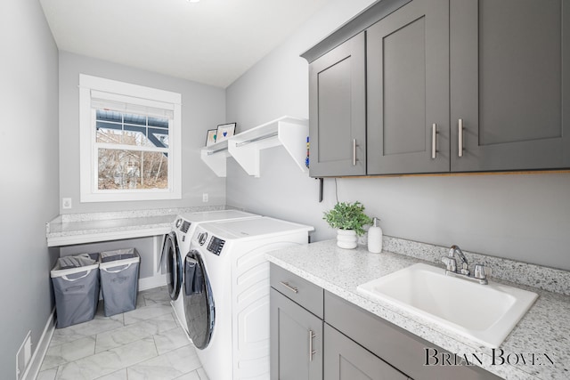 clothes washing area featuring washer and dryer, sink, and cabinets