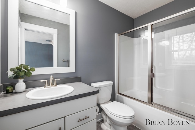 full bathroom featuring vanity, a textured ceiling, combined bath / shower with glass door, and toilet