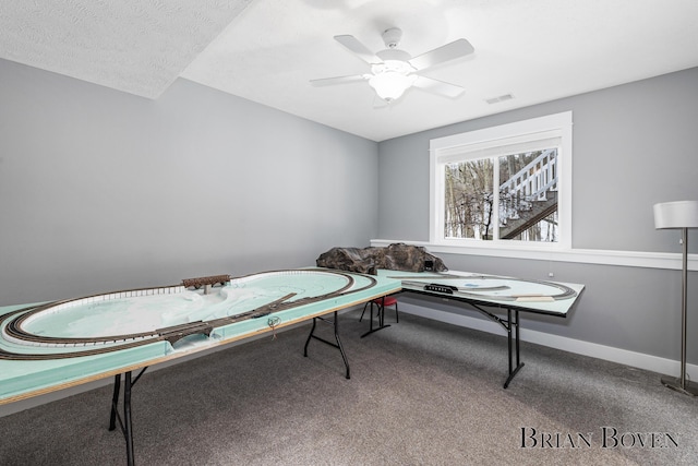 recreation room with ceiling fan, carpet floors, and a textured ceiling