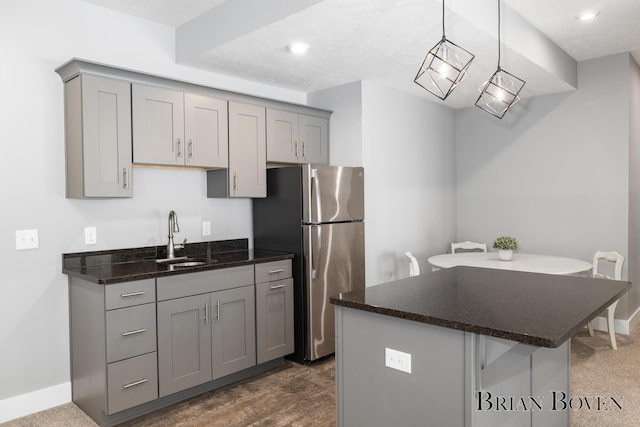 kitchen featuring gray cabinetry, sink, stainless steel fridge, and hanging light fixtures