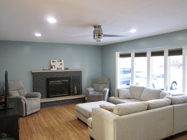 living room featuring ceiling fan, a fireplace, wood finished floors, and recessed lighting