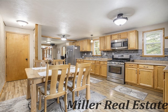 kitchen with appliances with stainless steel finishes, decorative backsplash, light hardwood / wood-style floors, and decorative light fixtures