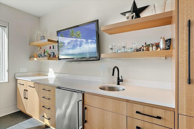 bar with light brown cabinetry, sink, dark tile patterned floors, and refrigerator