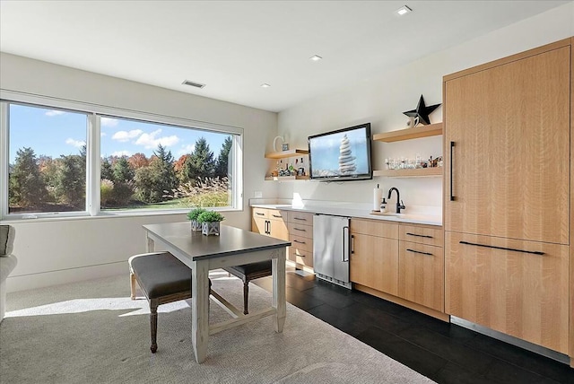 bar with refrigerator, light brown cabinetry, and sink