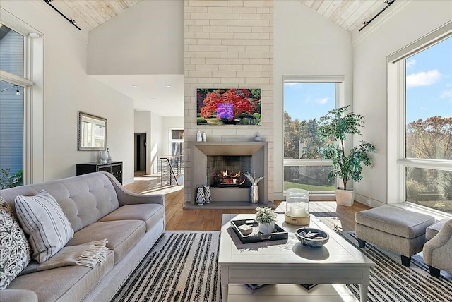 living room with hardwood / wood-style flooring, wood ceiling, high vaulted ceiling, and a brick fireplace