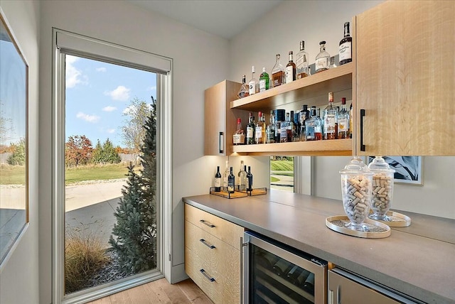 bar with beverage cooler and light wood-type flooring