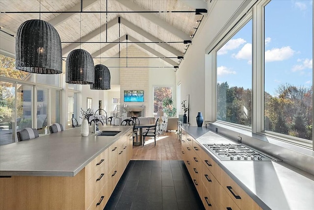 kitchen featuring a large island, light brown cabinetry, sink, and hanging light fixtures