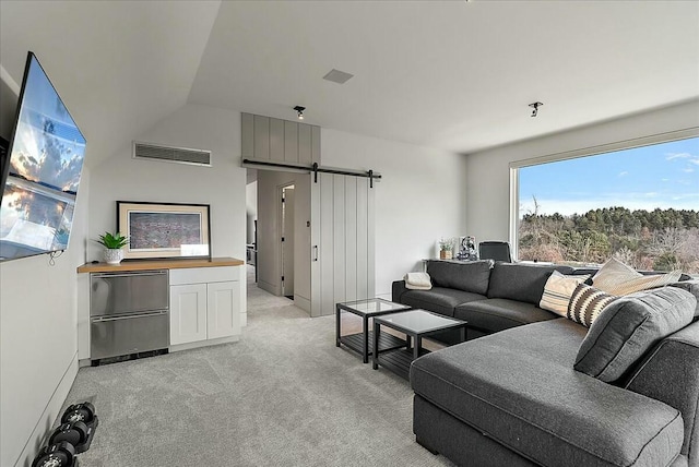 carpeted living room featuring a barn door and vaulted ceiling