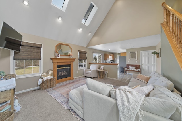 carpeted living room with a skylight and high vaulted ceiling