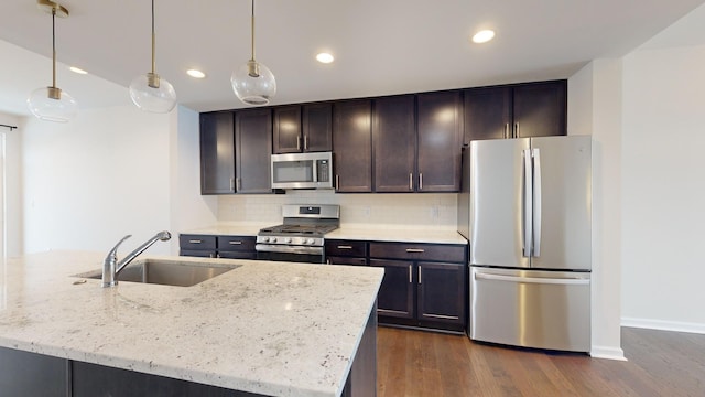 kitchen featuring decorative light fixtures, sink, stainless steel appliances, light stone countertops, and dark wood-type flooring