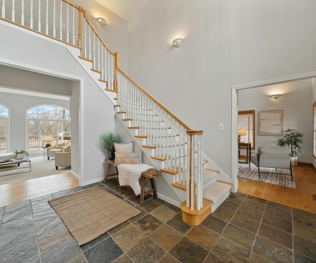 stairway with a towering ceiling and wood-type flooring