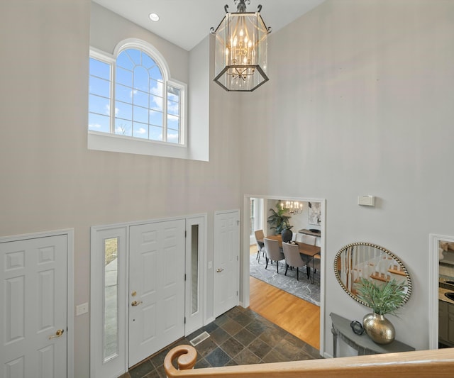 foyer featuring dark hardwood / wood-style floors, a towering ceiling, and an inviting chandelier