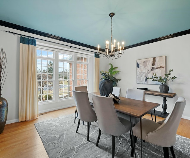 dining room with ornamental molding, wood-type flooring, and a notable chandelier