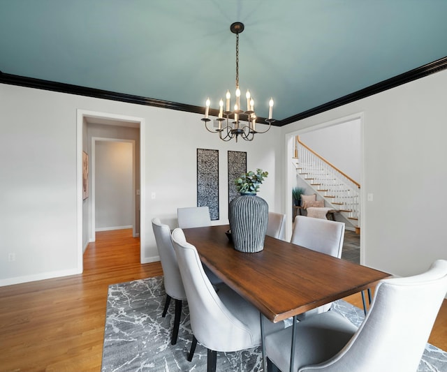 dining space featuring crown molding, hardwood / wood-style flooring, and a chandelier