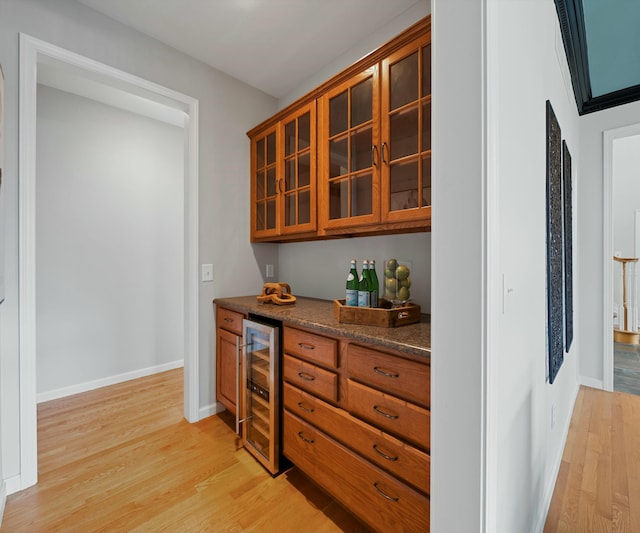 bar with light hardwood / wood-style floors and beverage cooler