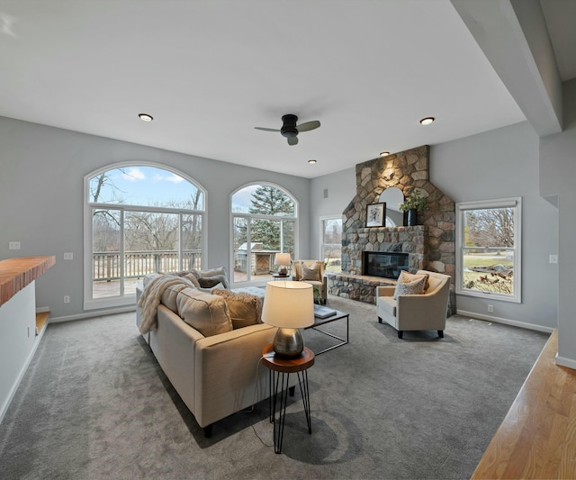 living room with dark hardwood / wood-style floors, ceiling fan, and a stone fireplace