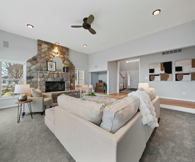 carpeted living room featuring a stone fireplace, a healthy amount of sunlight, lofted ceiling, and ceiling fan