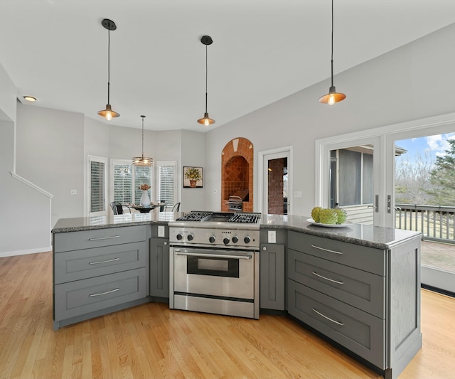 kitchen featuring gray cabinetry, hanging light fixtures, stainless steel stove, and light wood-type flooring