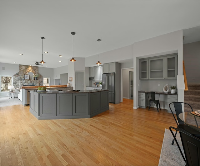 kitchen with decorative light fixtures, gray cabinets, light hardwood / wood-style floors, and appliances with stainless steel finishes