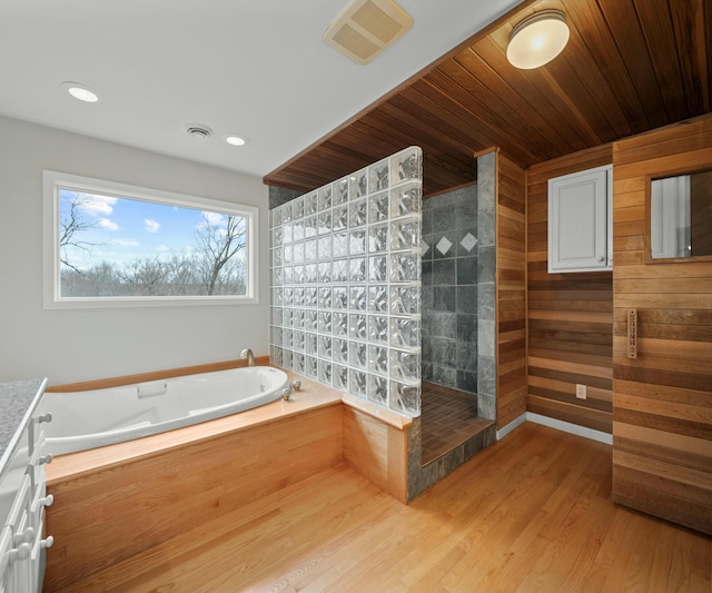 bathroom with wood walls, independent shower and bath, hardwood / wood-style flooring, vanity, and wooden ceiling