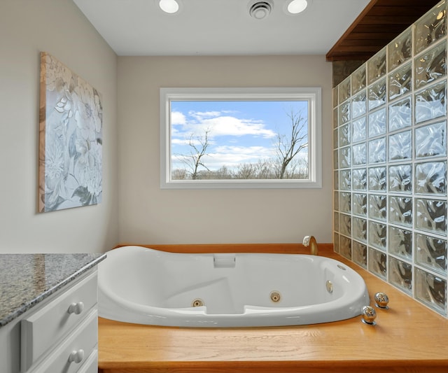 bathroom featuring vanity, tiled tub, and plenty of natural light